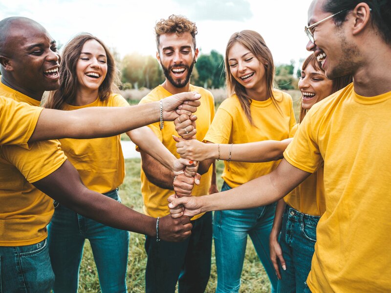 Multiracial happy young people stacking hands outside - Universi